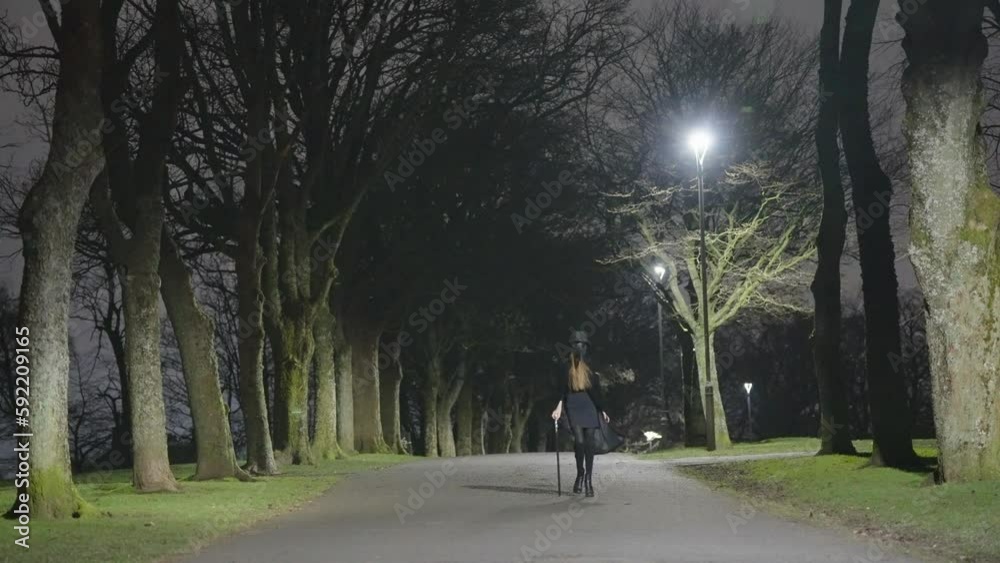A young female child dressed for Halloween as a plague Doctor walks in between trees at night A young female child dressed for Halloween as a plague Doctor walks in between trees at night