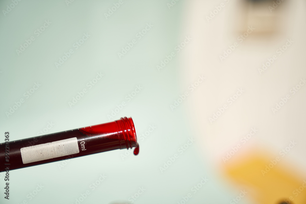 A transparent test tube for tests at an angle with red drop of blood on a light background. Selective focus. With a space to copy. High quality photo A transparent test tube for tests at an angle with red drop of blood on a light background. Selective focus. With a space to copy. High quality photo