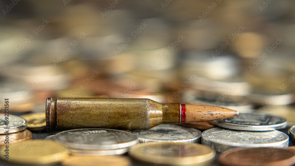 Bullet lies on a pile of coins, arms trade, blood money, world war