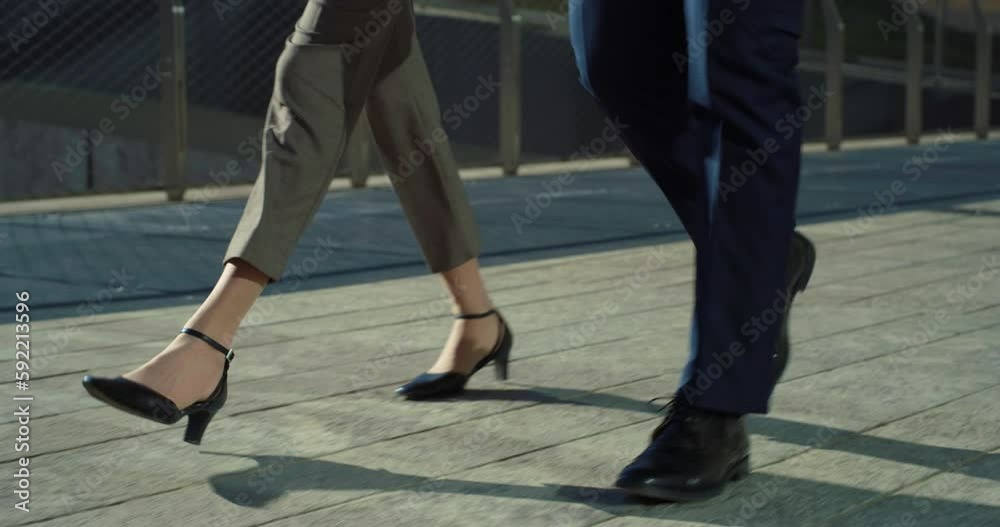 Ground Level Close Up of Male and Female Feet in Formal Shoes and Clothes Walking in City Street During Day. Successful Business Partners Going to Work in the Office While Discussing Strategy Ground Level Close Up of Male and Female Feet in Formal Shoes and Clothes Walking in City Street During Day. Successful Business Partners Going to Work in the Office While Discussing Strategy