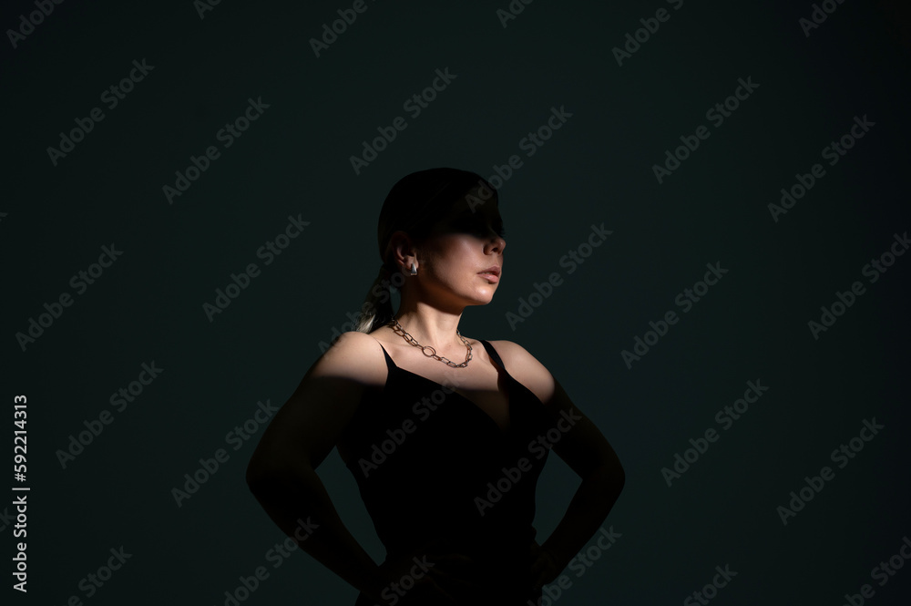 Woman in beam of light on black background, high contrast image