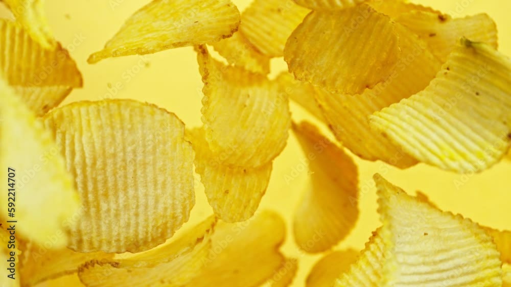 Super slow motion of rotating fried potatoes chips on yellow background. Filmed on high speed cinema camera, 1000 fps.