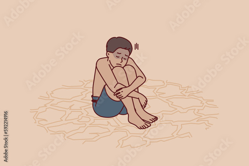 Sad boy feeling thirsty sits on dry ground after global climate change and pollution of ecological environment. Child suffers from lack of drinking water or drought that has destroyed rivers and lakes