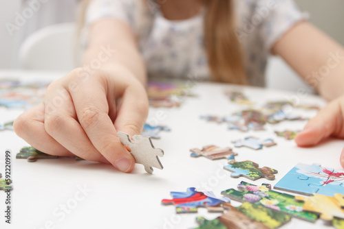 Little child picks up picture from pieces of puzzles