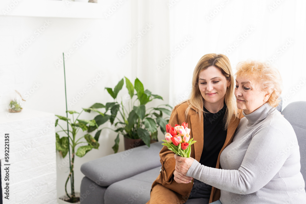 Happy mother's day. Beautiful young woman and her mother with flowers at home. Happy mother's day. Beautiful young woman and her mother with flowers at home.