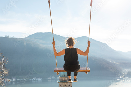 Woman on a Swing with Mountain View and Sunlight over Lake Lugano in Morcote, Ticino in Switzerland.