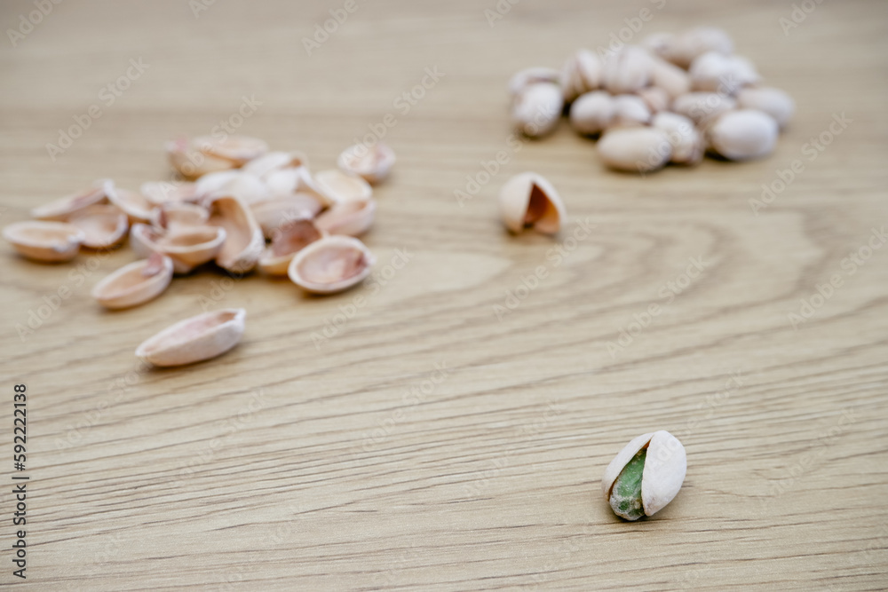 A pile of Pistachio nuts and nutshell on a wooden table. Pistachios background close-up, place for text.