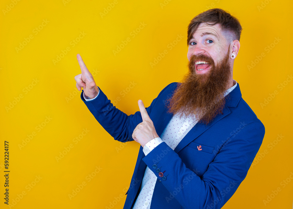Red haired man wearing blue suit over yellow studio background point at copyspace recommend sales discounts Red haired man wearing blue suit over yellow studio background point at copyspace recommend sales discounts