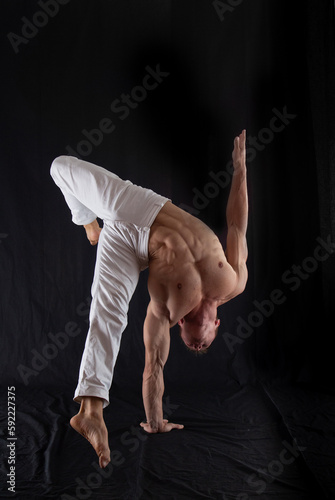 circus artist keeps balance on one hand isolated on a black background. Concept of individuality, creativity and self-confidence