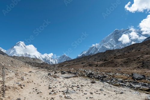 Beautiful view of a desert with a snowy mountain under cloudy sky © Ganga Raj Sunuwar/Wirestock Creators