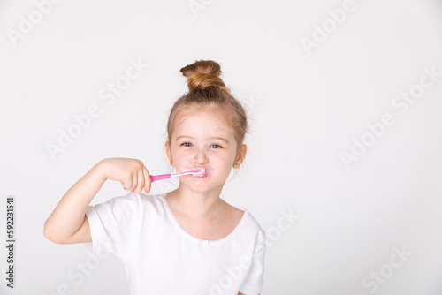 Happy child kid girl brushing teeth with toothbrush on white background. Health care, dental hygiene. Mockup, copy space