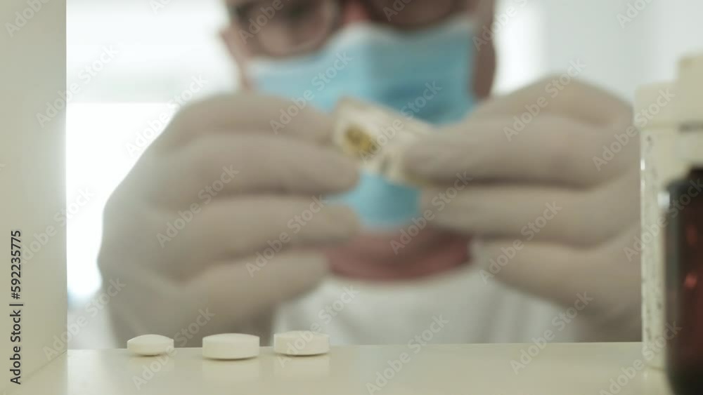 Medical Person Wearing Surgical Mask and Protective Gloves Taking Medical Pills Medical Person Wearing Surgical Mask and Protective Gloves Taking Medical Pills