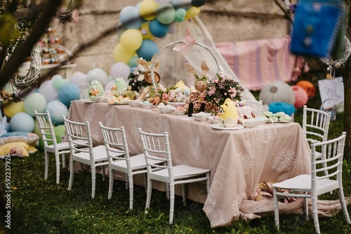 Table with food and cute decorations for a kid's birthday party in a garden in daylight