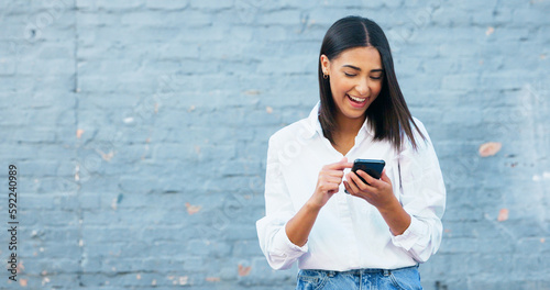 Fotografija Happy young woman texting on a phone and laughing in the city