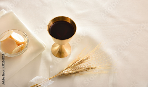 Fotografi Chalice and host with wheat spikes on white tablecloth