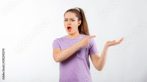 Shocked young woman with long hair pointing fingers right  looking concerned  showing smth upsetting  standing over white background