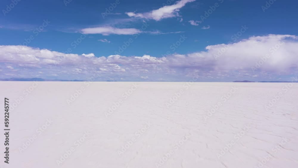 Uyuni Salt Flats on Sunny Day. Aerial View. Altiplano, Bolivia. Dry Season. Hexagonal Salt Formations and Crack Patterns. Drone Flies Backwards at Low Level. Wide Shot