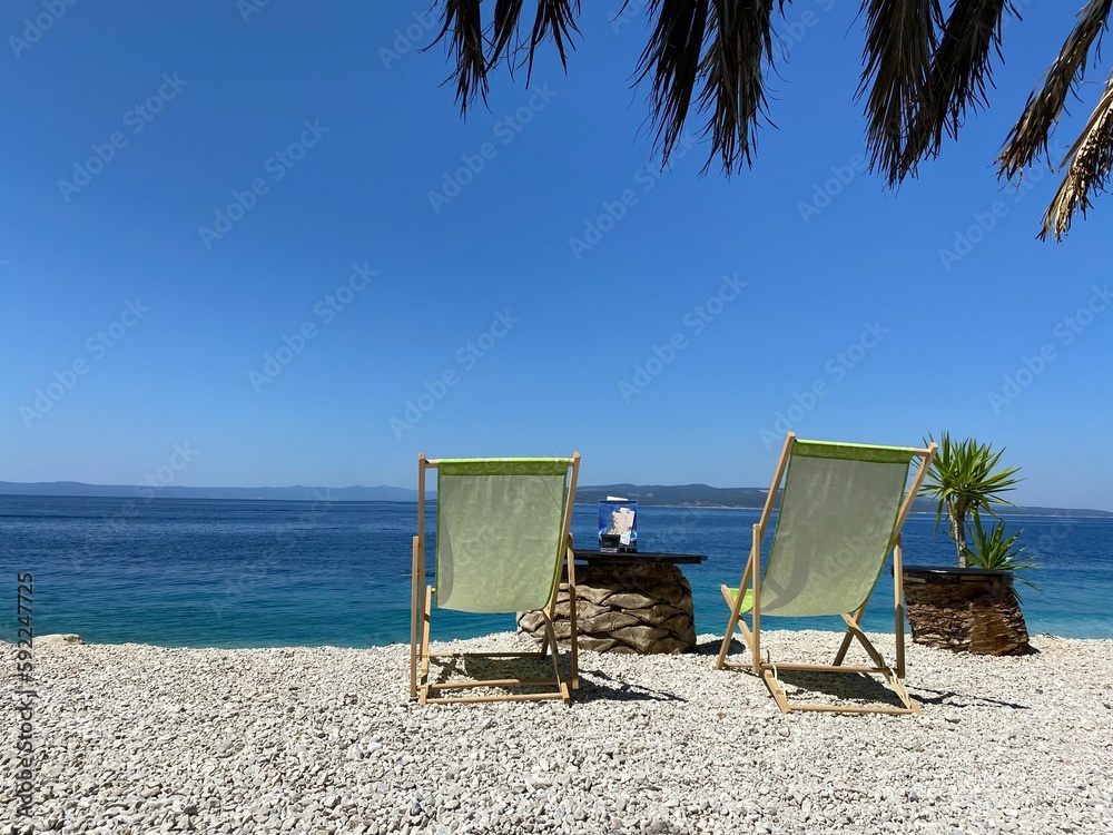 View of beach chairs on the beach in front of the blue sea