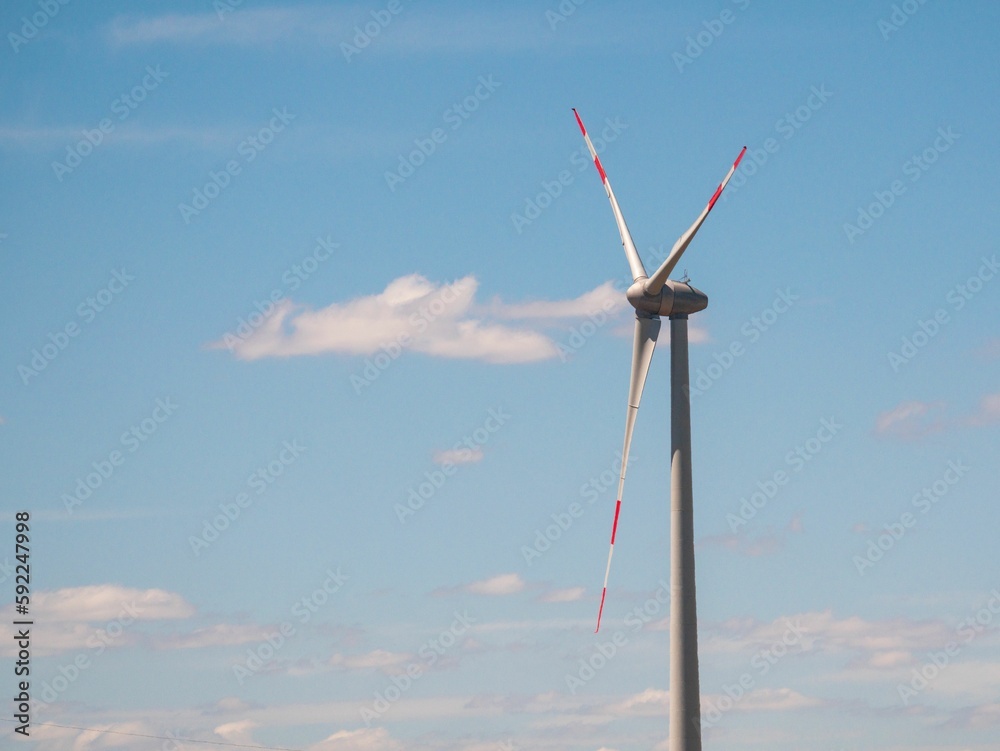Wind turbine in the countryside under a pale cloudy sky in a field on a sunny day Wind turbine in the countryside under a pale cloudy sky in a field on a sunny day