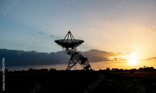 Silhouette shot of a radio telescope dish on a field during sunset