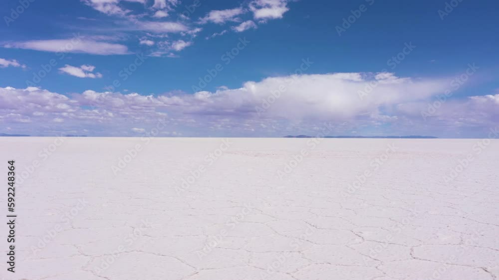 Uyuni Salt Flats on Sunny Day. Salar De Uyuni. Aerial View. Altiplano, Bolivia. Dry Season. Hexagonal Salt Formations and Crack Patterns. Drone Flies Sideways at Low Level. Wide Shot. Slider Shot