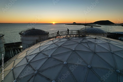 Workers on top of a sphere dome building near a coast during sunset © Abrahan Humberto Narcio Lopez/Wirestock Creators