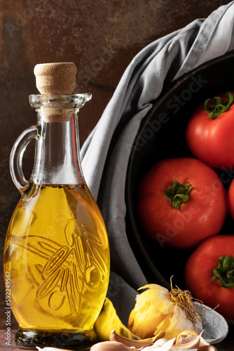 Fresh tomatoes in the pan and extra virgin olive oil on the dark background
