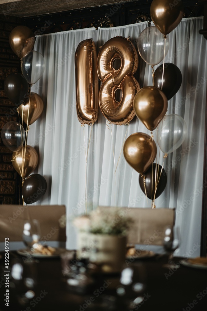 Vertical shot of an 18 birthday decoration with golden anniversary balloons on the white background Vertical shot of an 18 birthday decoration with golden anniversary balloons on the white background