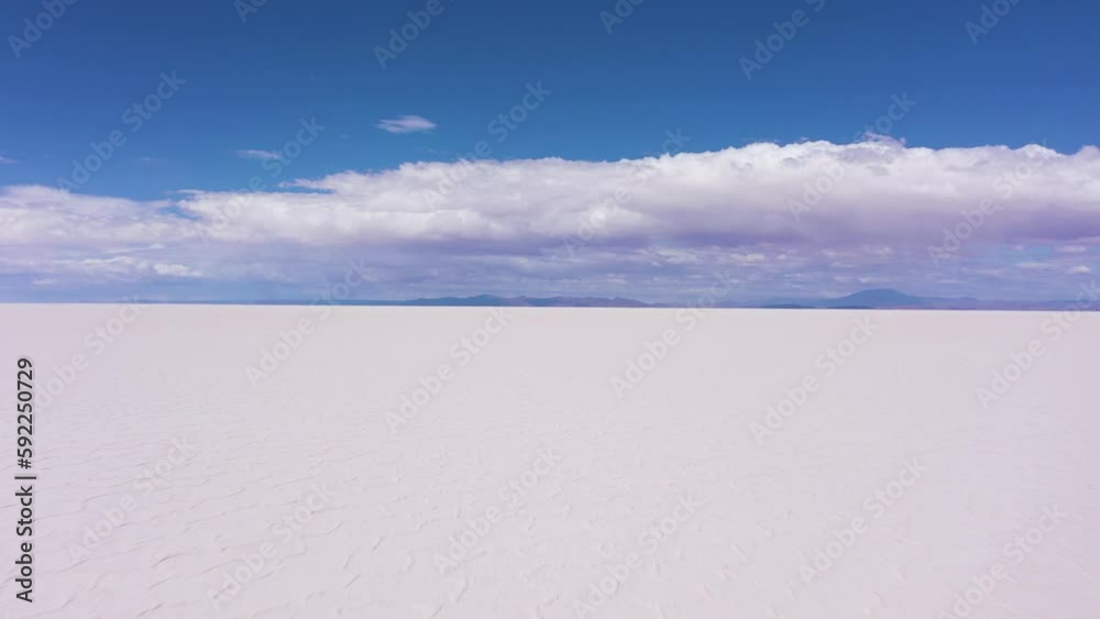 Uyuni Salt Flats on Sunny Day. Salar De Uyuni. Aerial View. Altiplano, Bolivia. Dry Season. Hexagonal Salt Formations and Crack Patterns. Drone Flies Backwards at Low Level. Wide Shot