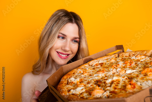 A beautiful fit young blonde girl with a big open pizza box. Isolated on yellow.