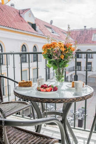 Cozy shot of outdoor balcony with fruit and sweet on table in background of buildings © Teemu Laitinen/Wirestock Creators
