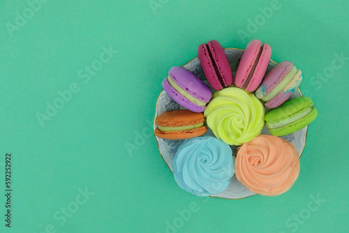 Traditional colored sweet desserts for the holiday. Marshmallows in plates on green background.