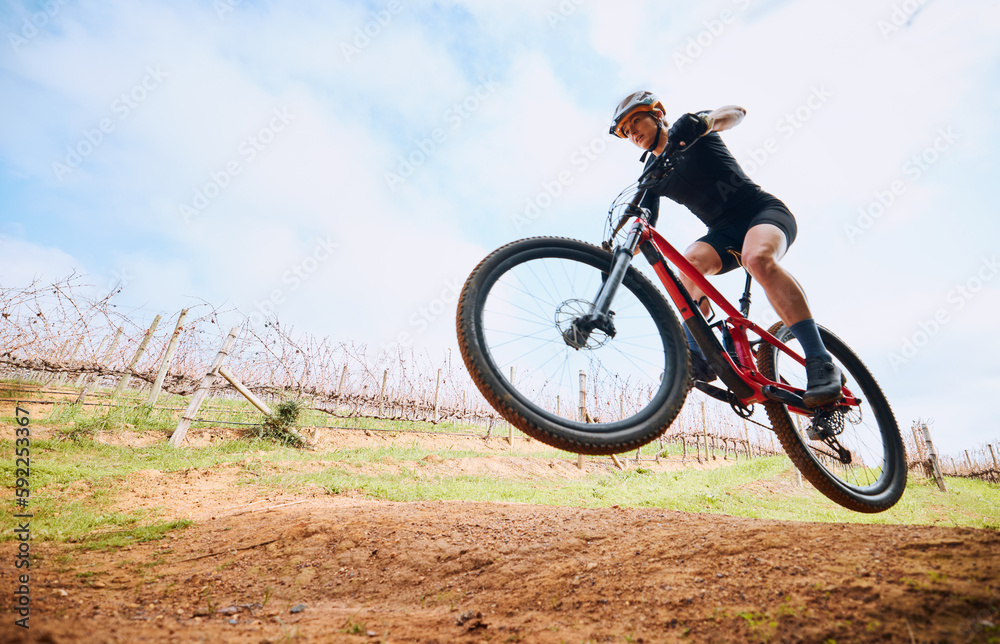 Bicycle jump, countryside and woman on a bike with speed for sports on a dirt road. Fitness, exercise and fast athlete doing sport training in nature on a park trail for cardio and cycling workout