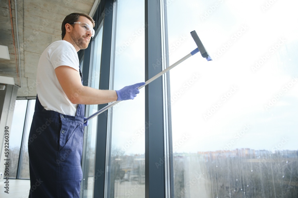 Male worker washing window glass