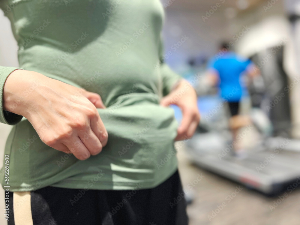 フィットネスジムでお腹をつまむ女性 フィットネスジムでお腹をつまむ女性