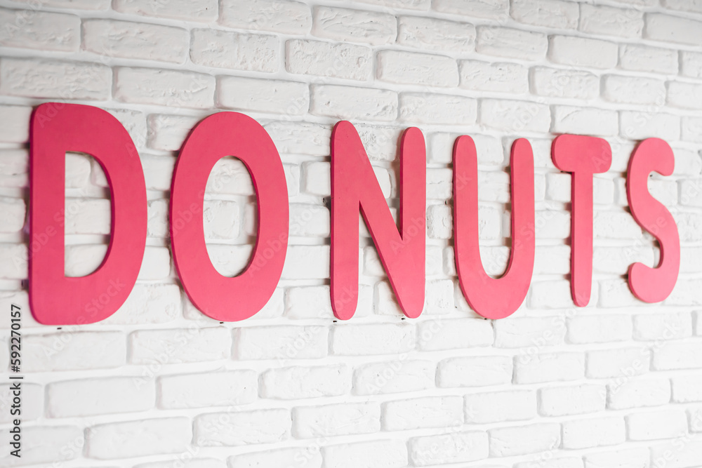 The word donuts on a white wall in a cafe, interior decor in a cafe with donuts, close-up lettering. The word donuts on a white wall in a cafe, interior decor in a cafe with donuts, close-up lettering.