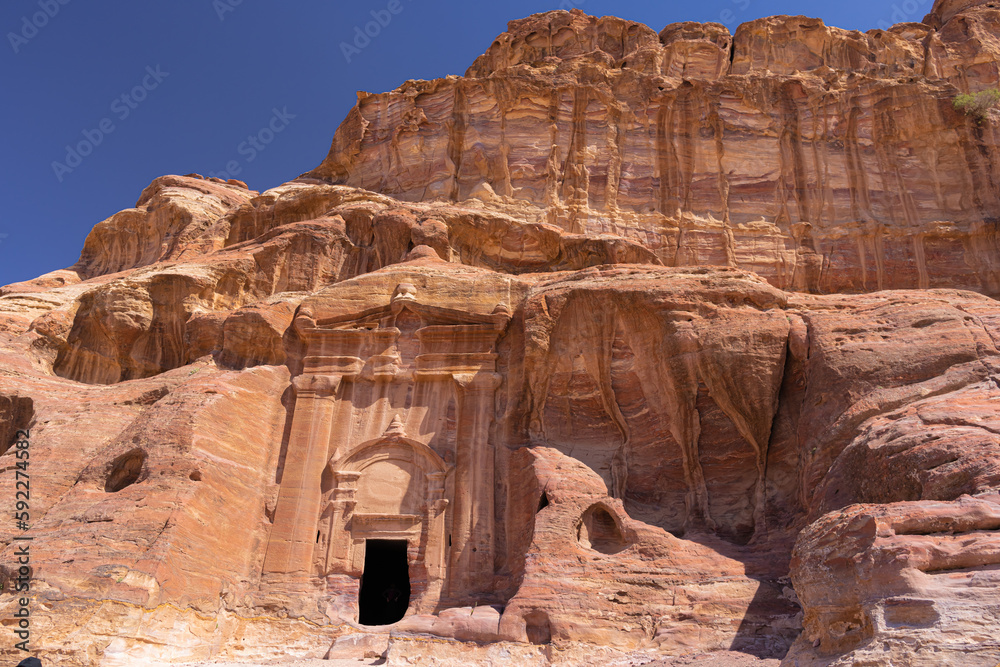 Fototapeta premium Petra w Jordanii. Ruiny starożytnego miasta w skale na tle błękitnego, bezchmurnego nieba.