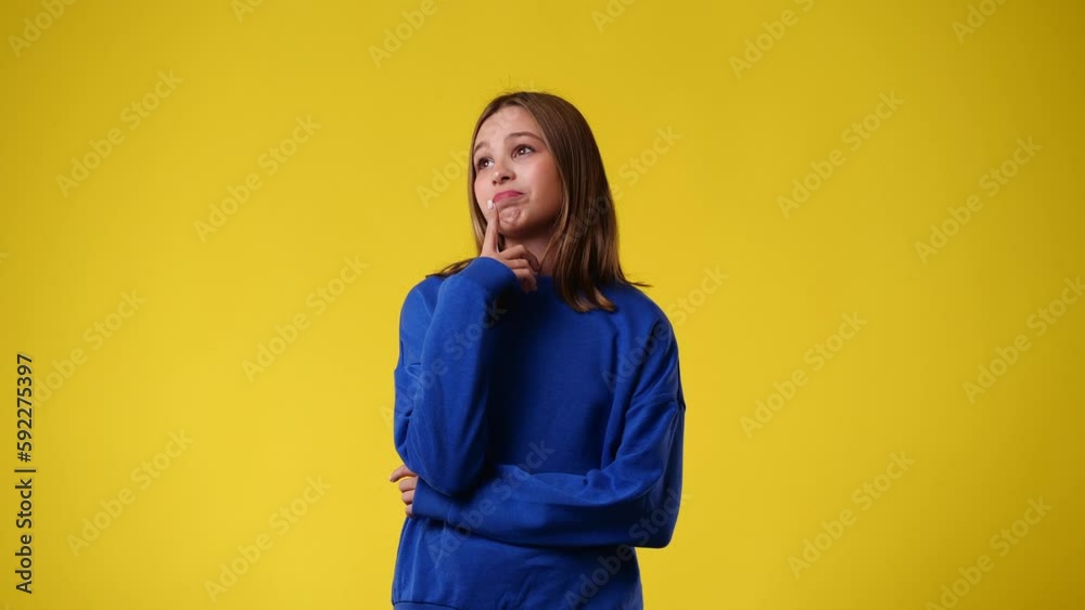 4k video of one young girl doubts and waving his hands around over yellow background.