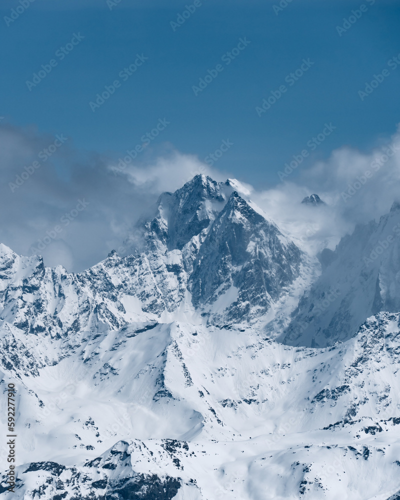 Snowy mountains in the clouds. Beautiful landscape with snowy rocks