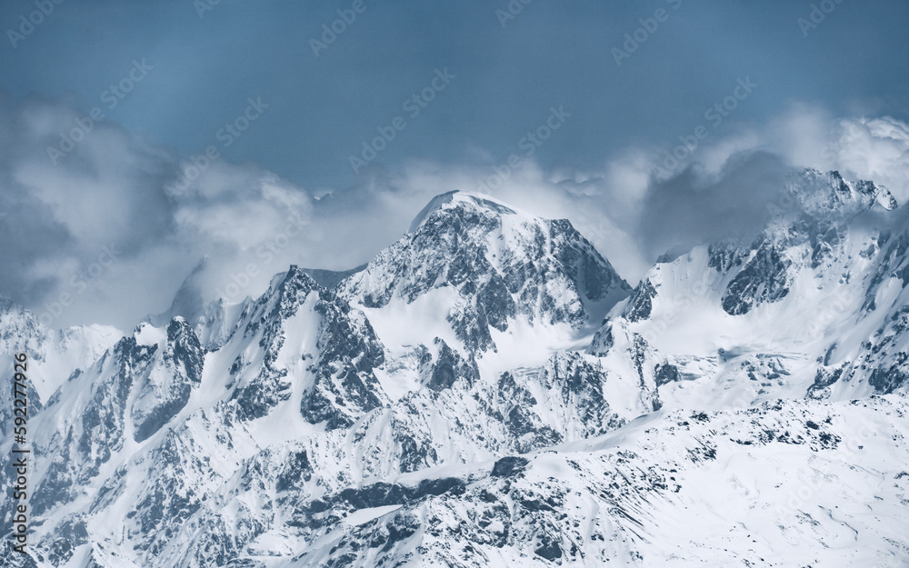 Alpine landscape with peaks covered with snow and clouds