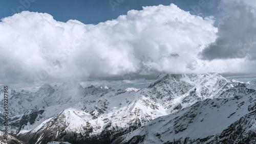 Alpine landscape with peaks covered with snow and clouds