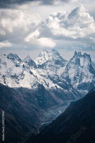 View of the valley and Mount Ushba and snow-covered peaks on a cloudy day © Maksim