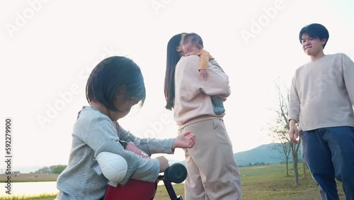 Asian young family enjoy spending time together on the weekend at outdoor recreation park, family time at warm season, parenting concept, happy asian parents and two children scene.