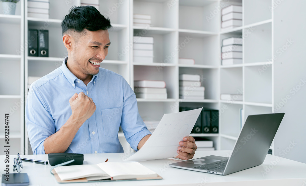 Naklejka premium Happy businessman celebrating a win raised up hands in light modern workstation
