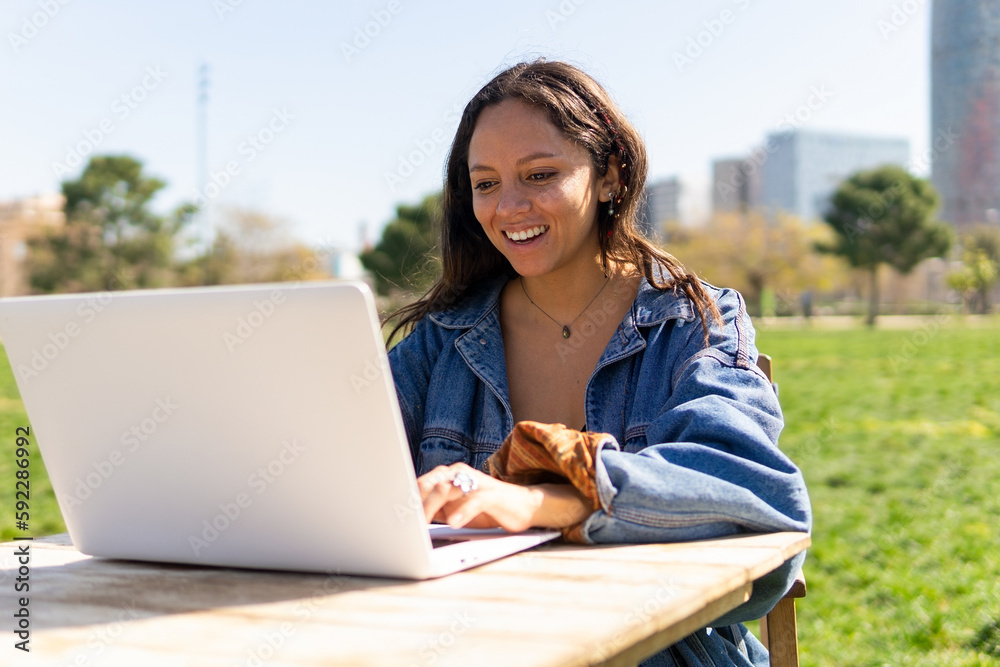 Smiling woman working on laptop in park Smiling woman working on laptop in park