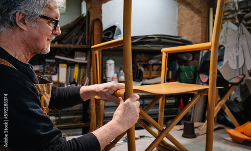 Canvas Print tanner placing the leather parts to a leather chair made by hand in a small shop in rome center