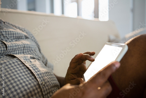 Midsection of man using digital tablet in living room