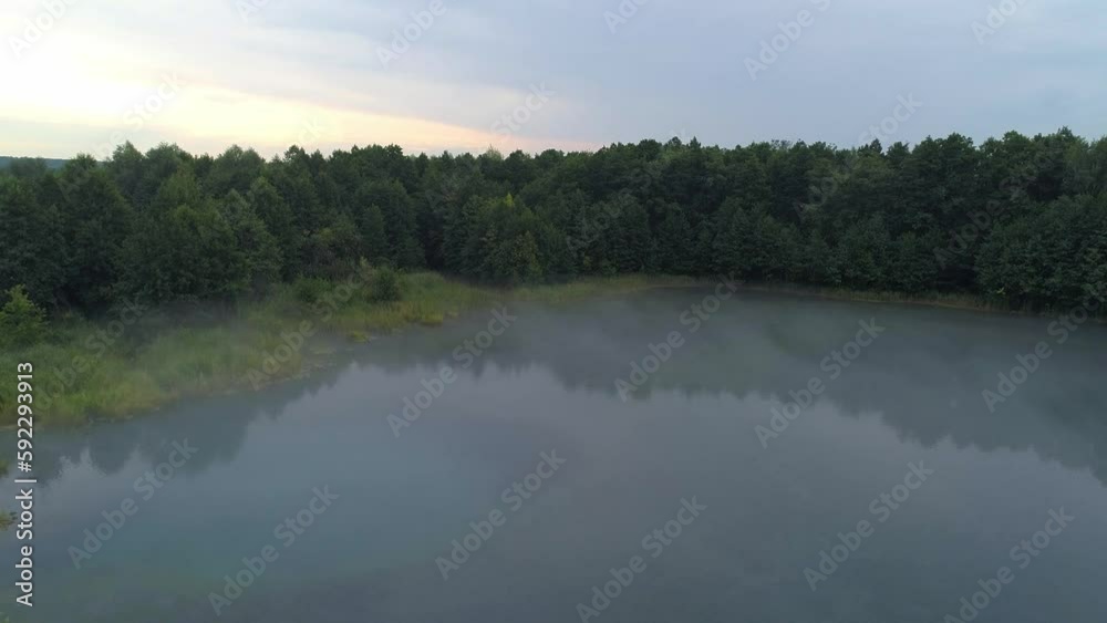 Early morning mist floating over calm water, lake. Aerial view flying slowly and low over a lake in fog. Early morning mist floating over calm water, lake. Aerial view flying slowly and low over a lake in fog.