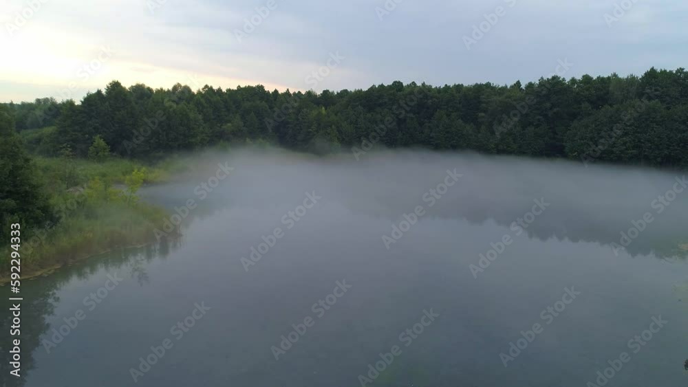 Early morning mist floating over calm water, lake. Aerial view flying slowly and low over a lake in fog. Early morning mist floating over calm water, lake. Aerial view flying slowly and low over a lake in fog.