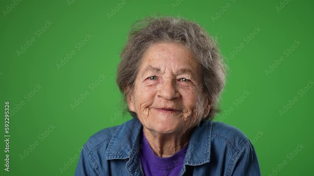 Closeup slow motion portrait of smiling happy toothless elderly senior old woman with wrinkled skin and grey hair isolated on green screen background in studio. Emotions concept